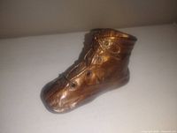 Front and side view of bronze baby boot shoe figurine showing laces and eyelet details.