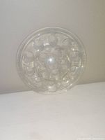 Top view of a clear glass flower frog showing multiple circular holes arranged in concentric circles.