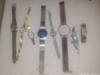 Collection of 8 vintage wristwatches in various styles and band materials laid flat on surface