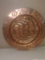 Front view of round copper plate showing hand hammered swirl design and edge details.