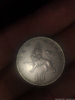 Close-up photo of a silver-colored English 10 pence coin featuring a lion, showing 'TEN PENCE' text and the number '10' on the face.