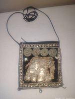 Small square handmade purse with elephant sequined applique and decorative bead details on front and thin strap shown on white background.