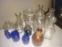 Collection of 11 old ink well bottles of various shapes and colors including clear, cobalt blue, and amber glass.