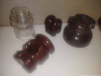 Seven vintage insulators, including four clear glass, two medium brown ceramic, and one larger dark brown ceramic insulator.