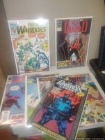 Photo showing six comic books in protective sleeves arranged on a surface, featuring various titles such as Punisher and El Diablo.