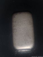 Rectangular hand poured pewter ingot on black background showing smooth rounded edges and textured surface.