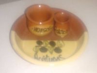 Photo of an oval pottery bowl in red and beige color with olives illustration and the word "Aceitunas", containing two small jugs labeled "Huesos" and "Palillos".