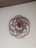 Clear image of a rose gold plated brooch pin with a central black onyx stone, showing its circular intertwined ribbon design.