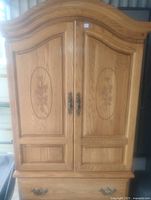 Front view of solid oak cabinet with carved floral designs on doors and metal handles
