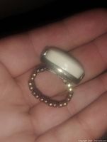 Close-up view of retro stretchy band ring held in hand, showing the creamy white stone and bronze-tone beaded band