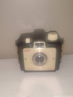 Front-facing image of a vintage Brownie camera showing lens, viewfinder, and body details