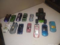 Top-down photo of 11 vintage toy cars in various colors and styles on a white surface.