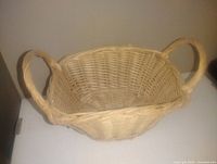 Wicker basket with two handles, light natural color, rectangular shape with rounded base, approximately 9 inches in size.