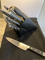 Full view of the knife block holding all cutting utensils and peeler, plus one chef knife laid out.
