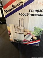 Photo of Moulinex compact food processor box showing product image and branding in red, white, blue colour scheme.