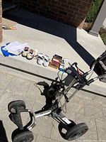 Overview of golf push cart, shoes, towels, gloves, and golf ball boxes on concrete surface