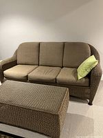Front view of three-seater resin wicker sofa with cushions and coffee table
