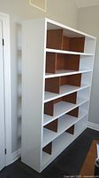 Front and side view of entire shelf unit showing white frame and faux wood dividers