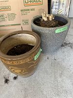 Photo showing two planters, one granite color approx. 17h x 18 dia and a brown ceramic approx. 16h x 15 dia with decorative design.