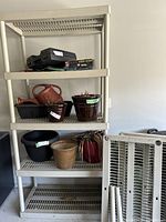 Full view of cream plastic shelving unit loaded with miscellaneous items (not included) showing structure and shelf design.