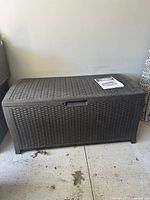 Front view of closed gray resin deck box with rattan texture