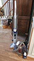 Full view of Bissell PowerFresh Deluxe 1806 upright steam floor cleaner and Bissell SpotClean 5207-1 portable spot cleaner with hose on wooden floor.