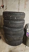 Five stacked tires leaning against concrete basement wall