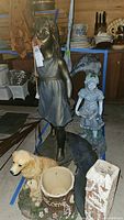 Photo showing resin dog statue with planter, resin child figure, and slate plaque in foreground, indoor setting with other kitchen items visible.
