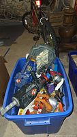 Blue plastic bin with assorted Ghostbusters proton guns and figure accessories