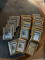 Overview of 19 silver and gold tone wooden picture frames arranged on a dark surface, showcasing two distinct color schemes and designs.