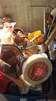 Photo showing mixed tools and accessories including sanding block, miter box, tape, and brushes piled together.