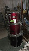 Stacked Mapex drums showing red shells and chrome hardware