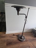Full view of entire gray metal Art Deco floor lamp showing round base, adjustable pole, arm, and shade