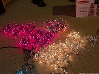 Four sets of Christmas string lights in red, multicolor, white, and blue, shown lit and tangled on carpeted floor.