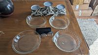 Four vintage Pyrex glass pie plates and metal candle centerpiece on wooden table