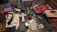 Overview photo showing all lot items including the Scrabble board, alarm clock, plaques, various small items, and the art supplies.