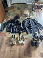 Photo of all items including black Nike raincoat, black suit jacket, two pairs of Sperry loafers, Sorel boots, and coat hangers on a carpet.