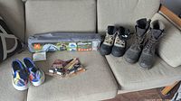 Photo showing all items including the unopened tent, two pairs of men's boots, Vera Bradley sneakers and wildlife warning wheel attachments on a couch.