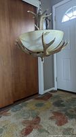 Full view of the Adirondacks style chandelier hanging in a living room with a frosted globe and faux antler horns forming the base.