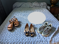 Blue chenille queen bedspread on bed with three pairs of women's shoes lined up at foot of bed.