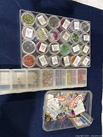 Containers displaying various cubic zirconia stones in different colors and sizes, with small round labeled boxes and compartment organizer visible.