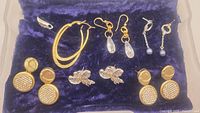 All six pairs of earrings displayed on a blue velvet background showing variety in styles and materials