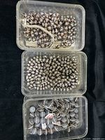 Three clear plastic containers filled with two shapes of silver-grey rice freshwater pearls accented with crystal spacers and one container with 16mm round grey agate beads with crystal spacers.