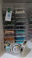 Stacked plastic containers filled with various beads in shades of orange, turquoise, blue, and green tones.