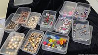 Eleven clear plastic cases filled with assorted beads including colored glass stars, pearlescent beads, faceted beads, and special shaped beads.
