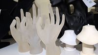 Three frosted acrylic ladies hands for ring display and two small white pendant displays on a shelf.