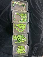 Plastic containers showing various sizes and shapes of dyed turquoise stones and beads in lemon and green colors.