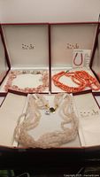Set of six necklaces displayed in branded Amalia Farrell boxes showing rose quartz chips, pink quartz beads, and coral baubles.