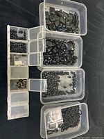 Top view of multiple plastic containers filled with faceted Onyx beads, chips, and gold filled bezel pieces.