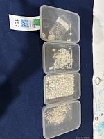Four plastic containers holding various freshwater pearls: mixed beads, necklace, coin pearls, and wired strands